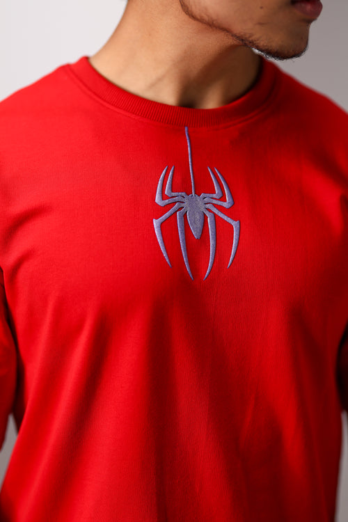 Red t-shirt with a spider logo worn by a person